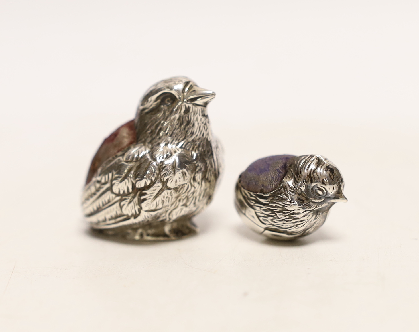 An Edwardian novelty silver pin cushion, modelled as a chick, Sampson Mordan & Co, Sheffield, 1905, height 40mm, together with a smaller hatching chick pin cushion, same maker, Chester, 1906.